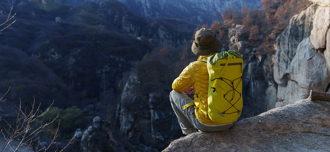 青年登山者坐在山顶俯瞰