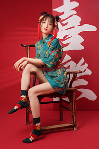 文字旗袍摄影照片_新年坐在椅子上的年轻女人
