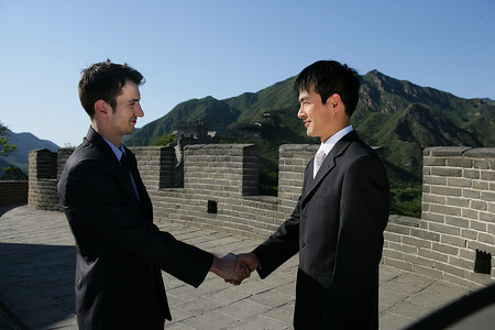 两位中外商务人士在长城上握手