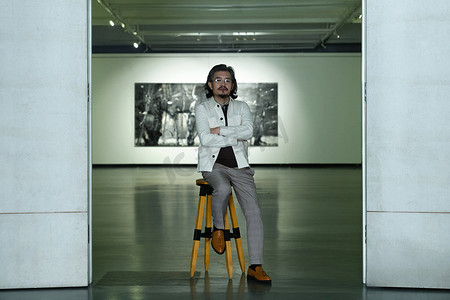 设计上的中国摄影照片_画展上的老艺术家坐在高凳上
