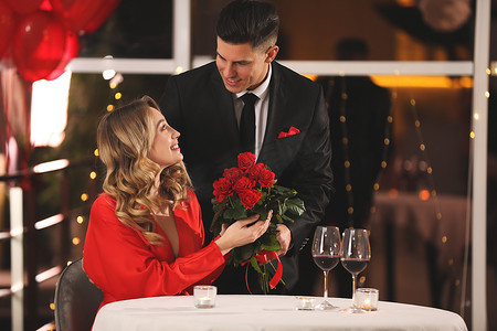 宴摄影照片_情人节宴会上，男人在餐馆向心爱的女人献上玫瑰