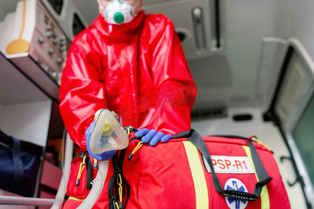 戴口罩的男性辅助医务人员在大流行病期间帮助救护车上的呼吸机病人
