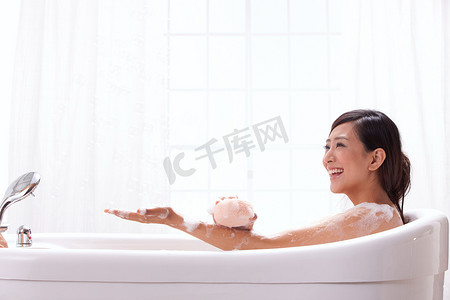 水龙头图片摄影照片_一个年轻女人坐在浴缸中
