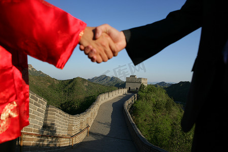中国传统人士与外国商务人士在长城上握手特写