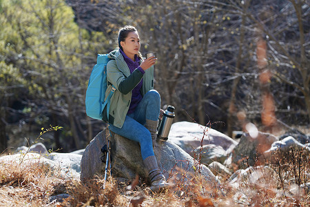 坐在石头摄影照片_徒步旅行的青年女人坐在石头上休息
