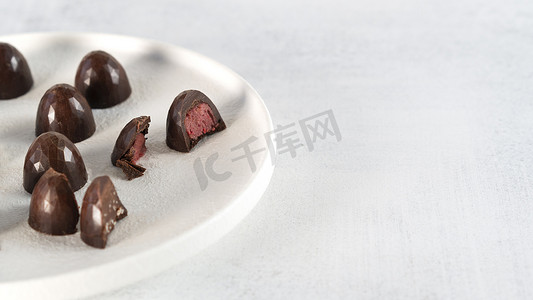 白盘上的自制黑巧克力糖果.覆盆子里塞满了糖果一块糖切成两半.