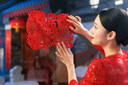 中式剪纸元素摄影照片_年轻女人过年贴窗花