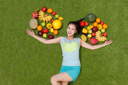年轻女子躺在草地上手托着水果