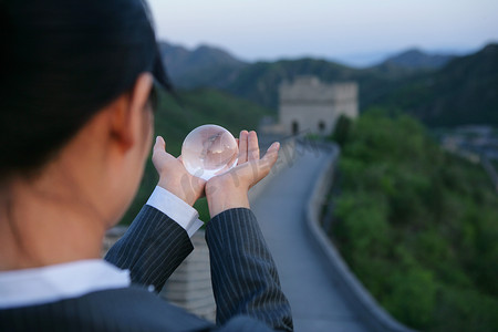 女商务人士在长城上手捧水晶地球