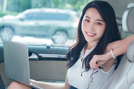 时尚年轻人摄影照片_漂亮的商务女性在汽车内使用电脑