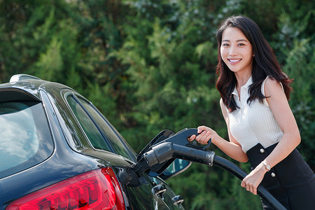 中国加油摄影照片_漂亮的青年女人给汽车充电