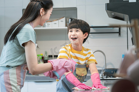 围裙摄影照片_年轻妈妈指导儿子在厨房打扫卫生