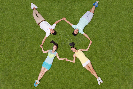 箭头环保标志摄影照片_青年男女手牵手躺在草地上