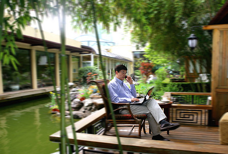 商务人士在酒店阳台使用手机和笔记本电脑