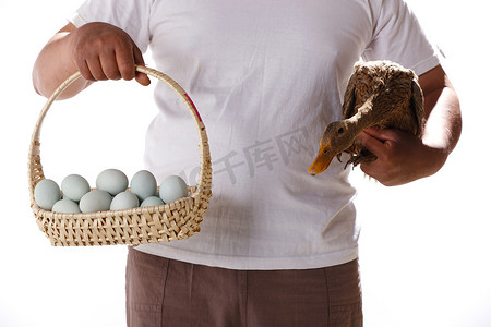 一个农民手拿鸭子和鸭蛋