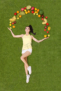 t恤多色摄影照片_年轻女子手托着水果躺在草地上