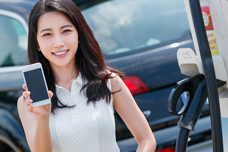 中国加油摄影照片_青年女人使用手机自助充电汽车