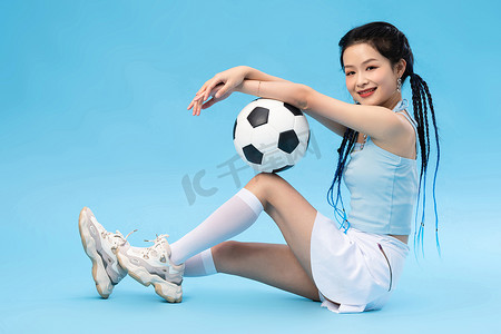蓝色背景简洁摄影照片_年轻女孩和足球