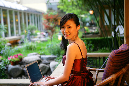 年轻女士在酒店阳台使用笔记本电脑肖像