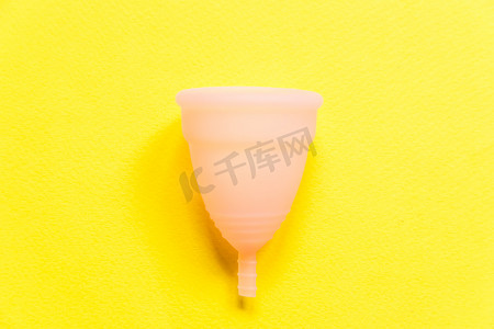 简单的设计粉红月经杯在黄色背景上隔离。妇女在月经期间可选择现代生态妇科卫生.装血的容器平面放置顶视图复制空间