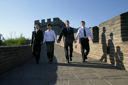 四位中外商务人士在长城上牵手行走