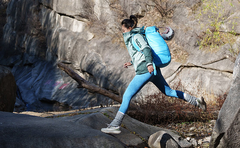 徒步旅行的青年女人跨过石涧