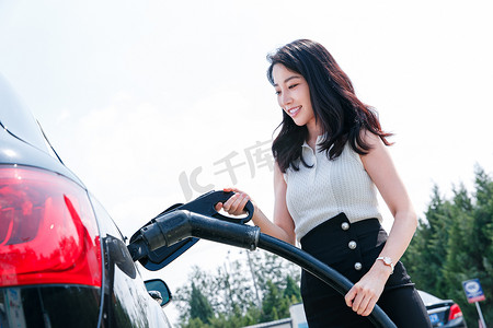 中国加油摄影照片_漂亮的青年女人给汽车充电