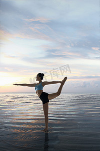 瑜伽动作摄影照片_年轻女人在水面上练习瑜伽