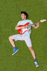 年轻男子躺在草地上弹吉他