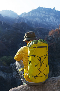 青年登山者坐在山顶俯瞰