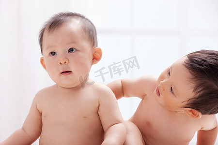人体白色摄影照片_两个婴儿坐在室内床上