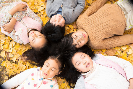 银杏叶秋摄影照片_可爱的男孩女孩躺在地上