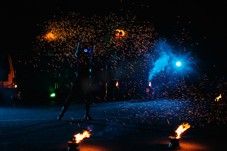 火灾表演，与火焰共舞，男性大师与烟火共舞，在户外表演，在黑暗中画出一个火热的身影，在夜晚明亮的火花。一个穿着LED西服的男人与火共舞.