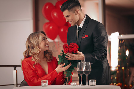 情人节宴会上，男人在餐馆向心爱的女人献上玫瑰