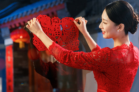中式福字装饰摄影照片_年轻女人过年贴窗花