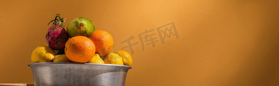 橙色背景的金属碗中奇异的水果，横幅