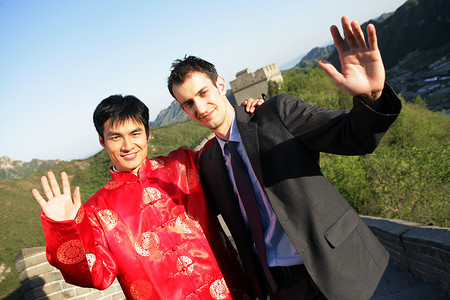 招手动作摄影照片_中国传统人士与外国商务人士在长城上站立挥手