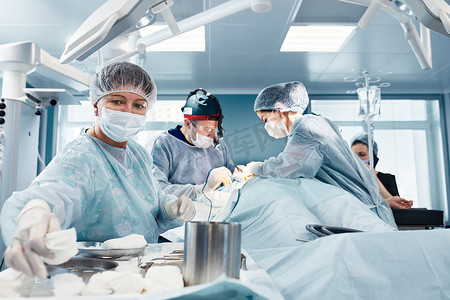 在一个真正的手术中，一位女外科医生在一个现代手术室的一组外科医生的帮助下，在整形手术中提供了一些器械，从而挽救了生命.