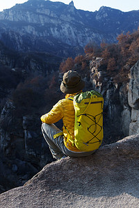 青年登山者坐在山顶俯瞰