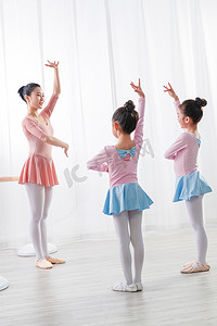 可爱芭蕾摄影照片_年轻舞蹈老师教小女孩们跳芭蕾