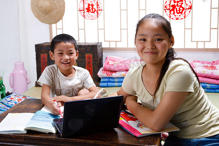 中国传统成长摄影照片_姐弟两人在家写作业看电脑