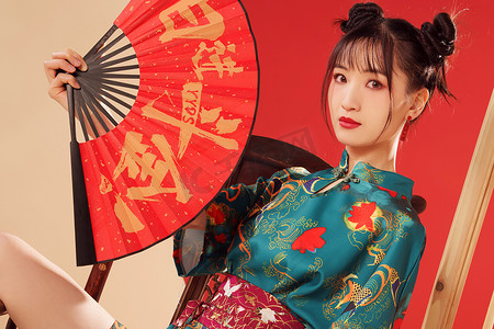 春节扇子扇子摄影照片_新年拿着扇子的年轻女人