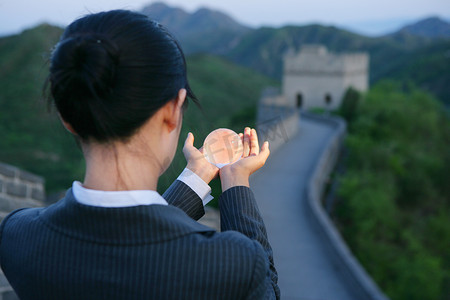 女商务人士在长城上手捧水晶地球