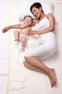 躺着休息摄影照片_母亲和婴儿躺在床上休息