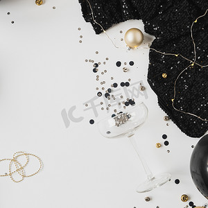圣诞/新年假期庆祝概念。金色，黑色领带，香槟杯，白色背景的女装。平面，顶部视图.