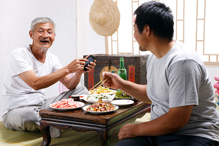 电子产品中摄影照片_农民父子坐在家中吃饭打电话