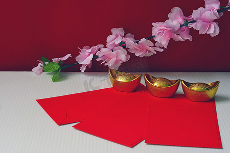 春节装饰品或红包金块或金块镶嵌在红色的背景上，梅花盛开，吉祥吉祥，财源滚滚.