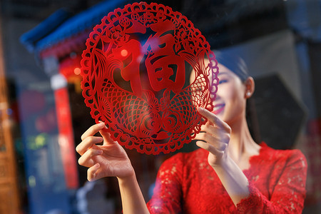 传统节日剪纸装饰摄影照片_年轻女人过年贴窗花