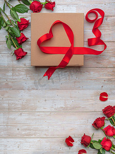 心形彩带摄影照片_大型工艺礼品盒心形彩带装饰,豪华玫瑰,木制表面.