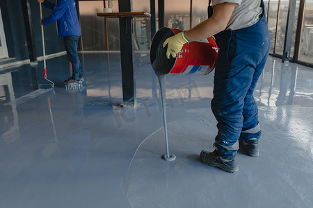 工人把灰色环氧树脂涂在新地板上